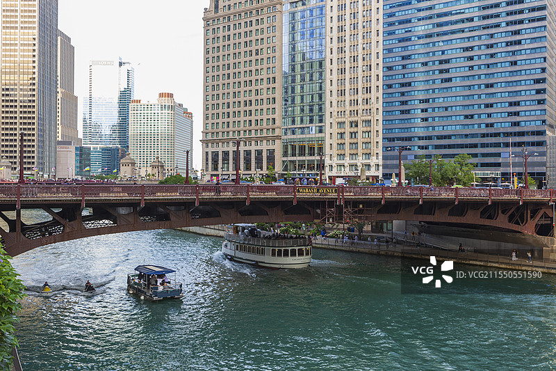 晴朗夏日，铁桥横跨芝加哥河上，观光船往来，两岸高楼林立。图片素材