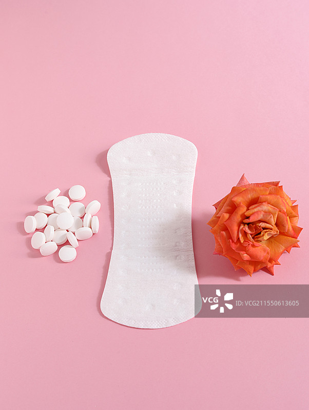 粉色背景上的女性月经用品卫生巾卫生棉和痛经止痛药图片素材