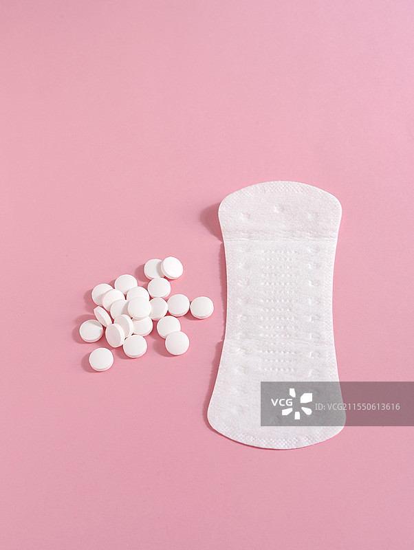 粉色背景上的女性月经用品卫生巾卫生棉和痛经止痛药图片素材