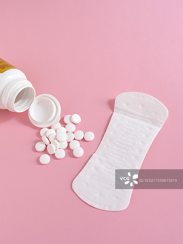 粉色背景上的女性月经用品卫生巾卫生棉和痛经止痛药图片素材