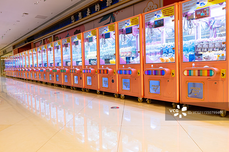 中国游戏机拍摄主题，成一排的夹娃娃机机器设备用品和里面各种各样的布娃娃公仔，室内无人图像摄影图片素材