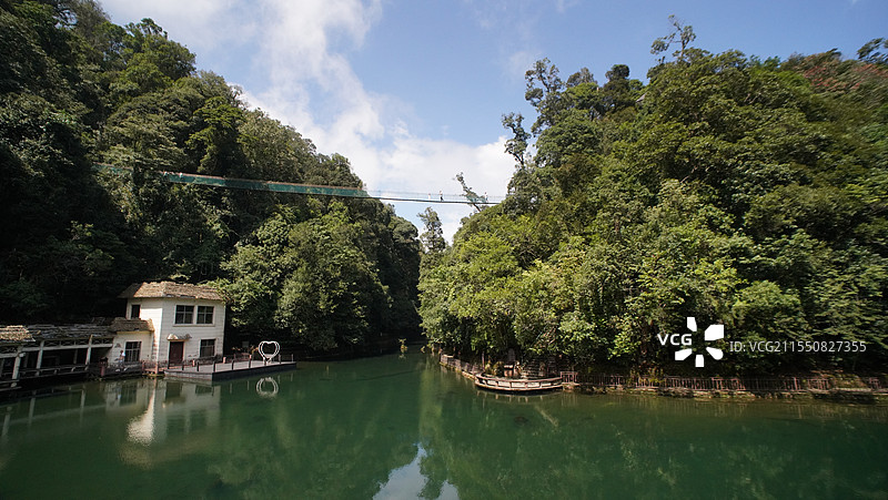 云南红河州的蔚蓝湖水与森林吊桥图片素材