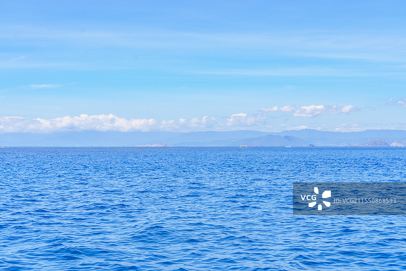 晴朗的天气，印度尼西亚努沙登加拉龙目岛外蔚蓝的大海，蓝色天空上飘着白云图片素材