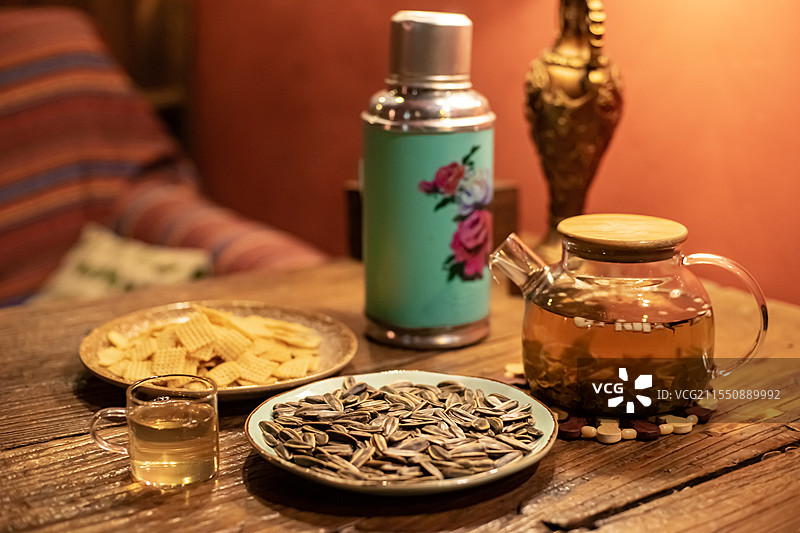 中国休闲娱乐健康生活方式拍摄主题，木制桌子上一堆黄色的锅巴瓜子小吃暖水壶和玻璃杯，室内无人图像摄影图片素材