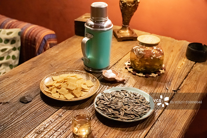 中国休闲娱乐健康生活方式拍摄主题，木制桌子上一堆黄色的锅巴瓜子小吃暖水壶和玻璃杯，室内无人图像摄影图片素材