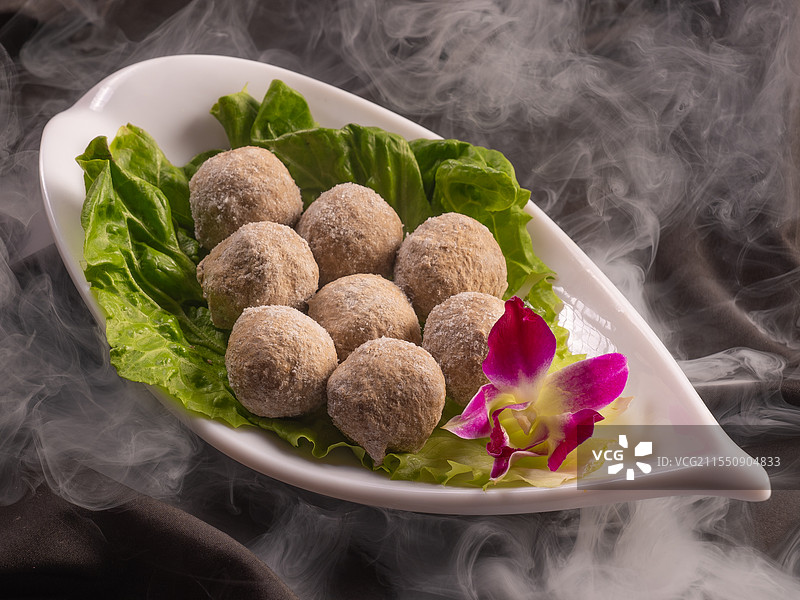黑色带白色烟雾背景上的牛丸装盘火锅店涮锅菜品图图片素材
