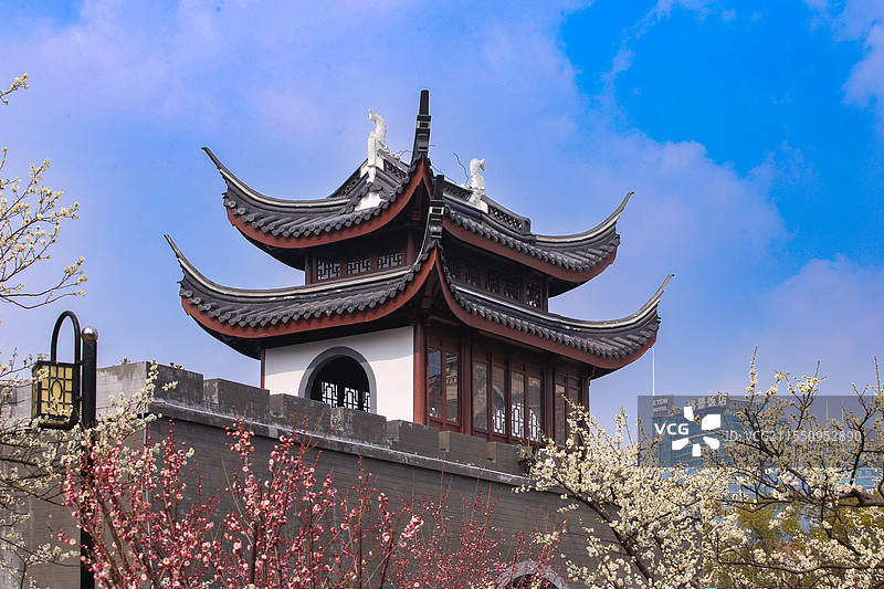 飞檐翘角，古韵悠然。在蓝天白云下，中式阁楼静立，城墙古朴。繁花簇拥，历史与自然在此交融。图片素材