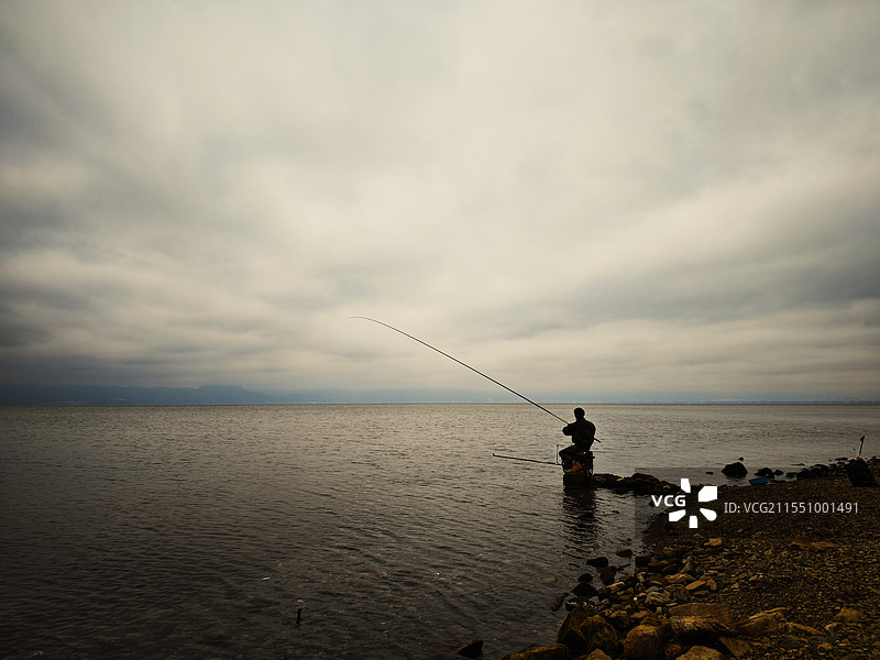 阴天独自一人在抚仙湖边钓鱼的人•云南省玉溪市抚仙湖图片素材