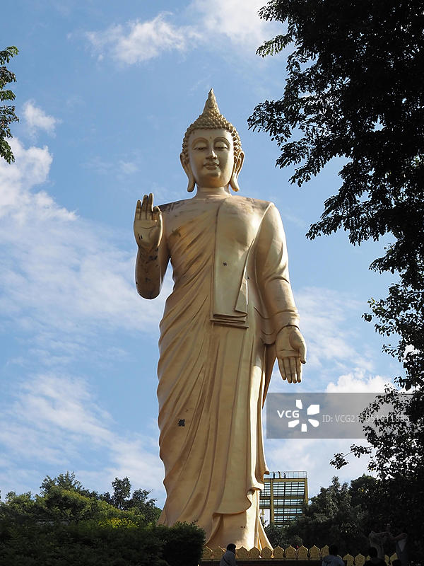 2024年11月5日云南西双版纳勐泐大佛寺的佛祖佛像在蓝天多云天空下的低角度佛像正面图图片素材