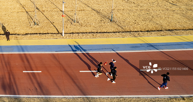 红色跑道上正在跑步的人群和倒影图片素材