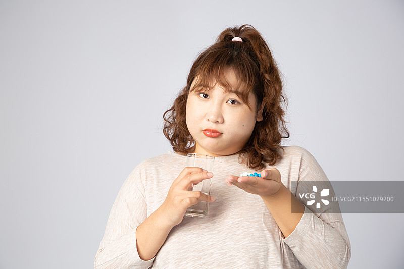 正在吃药的亚洲肥胖女孩图片素材