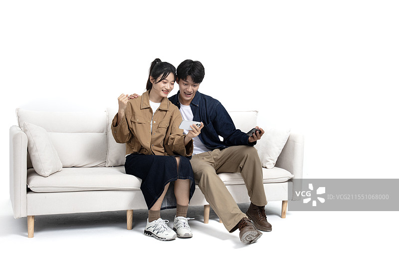 坐在沙发上玩手机视频的年轻男女图片素材