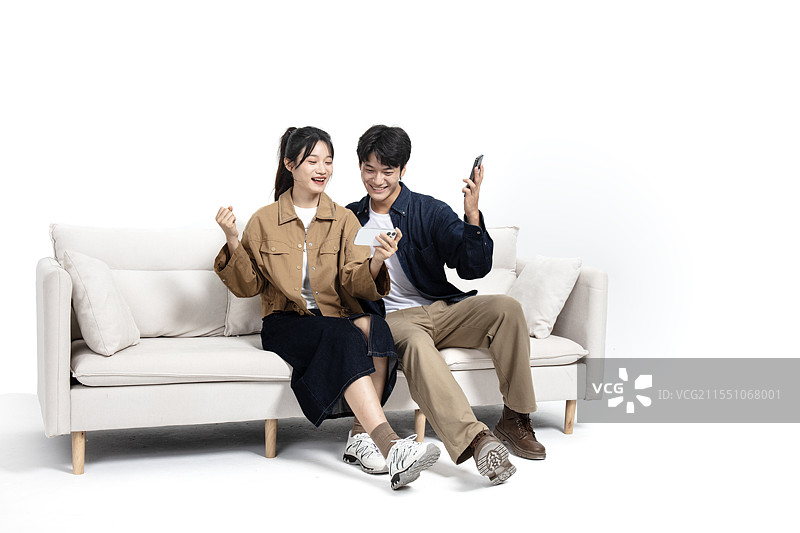 坐在沙发上玩手机视频的年轻男女图片素材