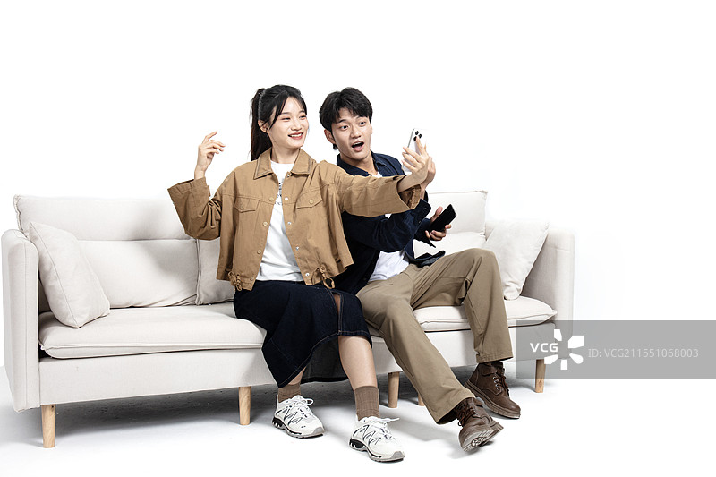 坐在沙发上玩手机视频的年轻男女图片素材