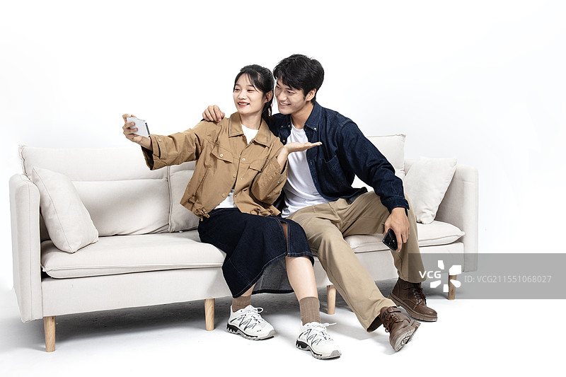 坐在沙发上玩手机视频的年轻男女图片素材