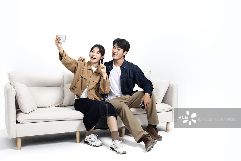 坐在沙发上玩手机视频的年轻男女图片素材