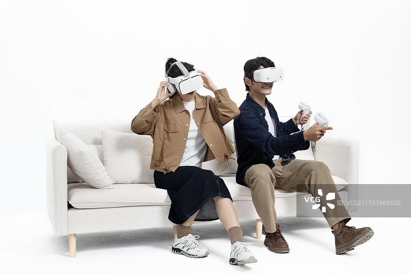 坐在沙发上玩VR游戏的年轻情侣图片素材
