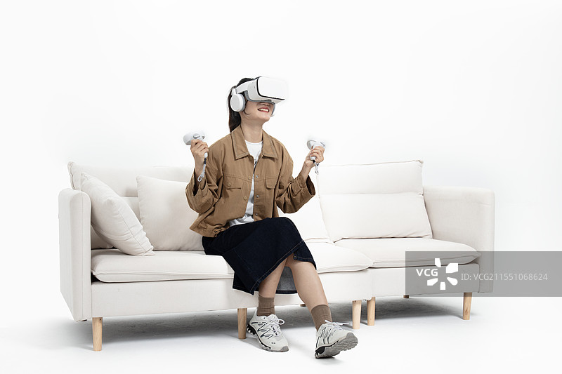 坐在沙发上玩VR游戏的年轻女人图片素材
