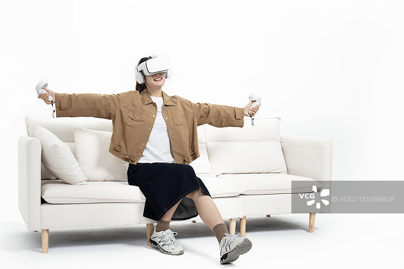 坐在沙发上玩VR游戏的年轻女人图片素材