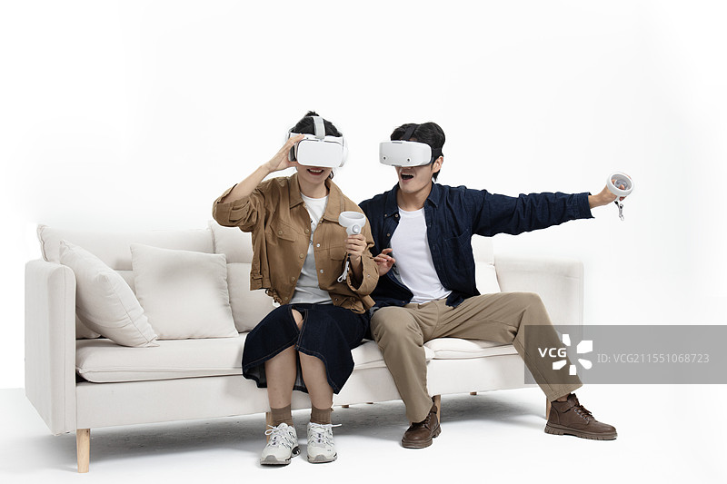 坐在沙发上玩VR游戏的年轻情侣图片素材