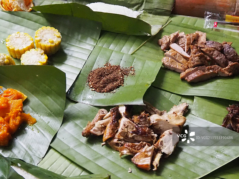 2024年11月6日云南西双版纳基诺山雨林徒步人们在山里的野外竹屋享用基诺山里的芭蕉叶上天然食物特写图片素材
