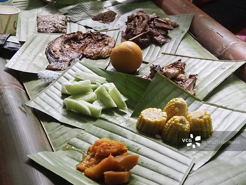 2024年11月6日云南西双版纳基诺山雨林徒步人们在山里的野外竹屋享用基诺山里的芭蕉叶上天然食物特写图片素材