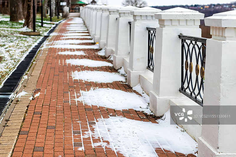 公园里铺设的小路覆盖着冬季的第一场雪。冬季天气或初雪概念。图片素材