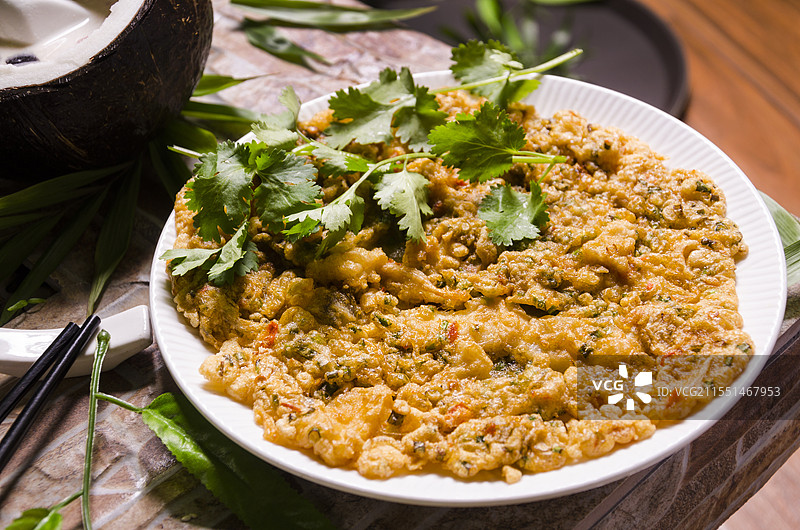 一盘表面撒有香菜的煎蛋饼摆放在白色盘子里。图片素材