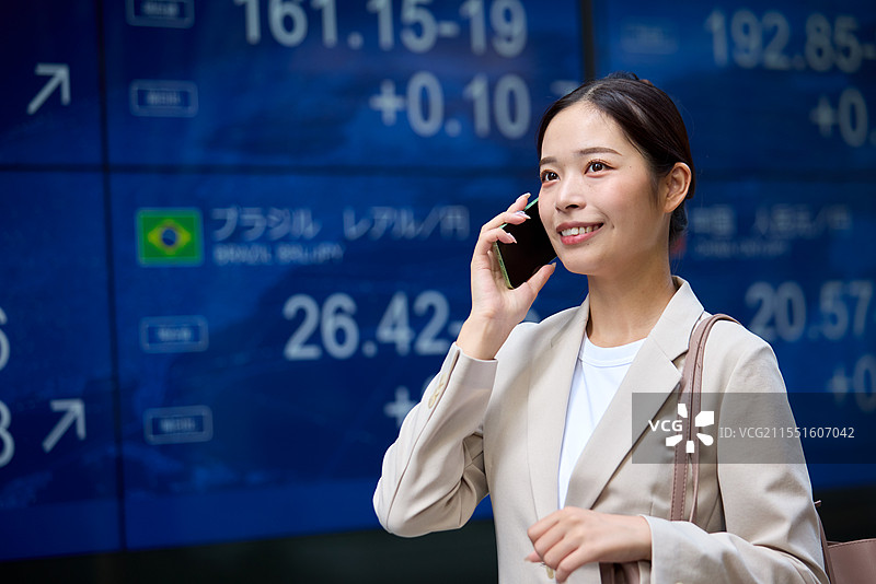 在股市前面打电话的日本女性图片素材