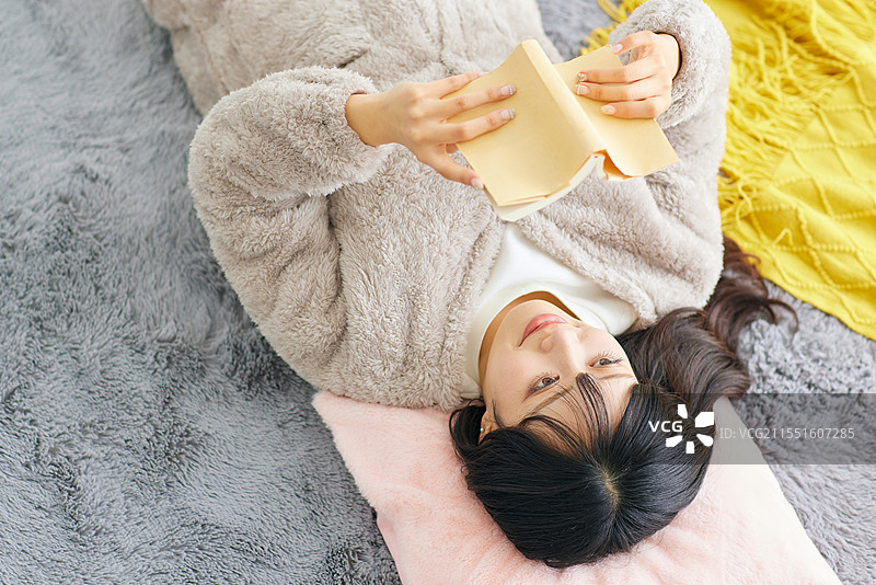 穿着毛茸茸外套的日本女性在阅读一本书图片素材