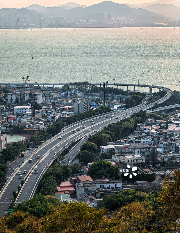 城市脉络从高处凝望，蜿蜒公路如丝带穿梭于城市间，一头连着烟火人间，一头系着浩渺大海。图片素材