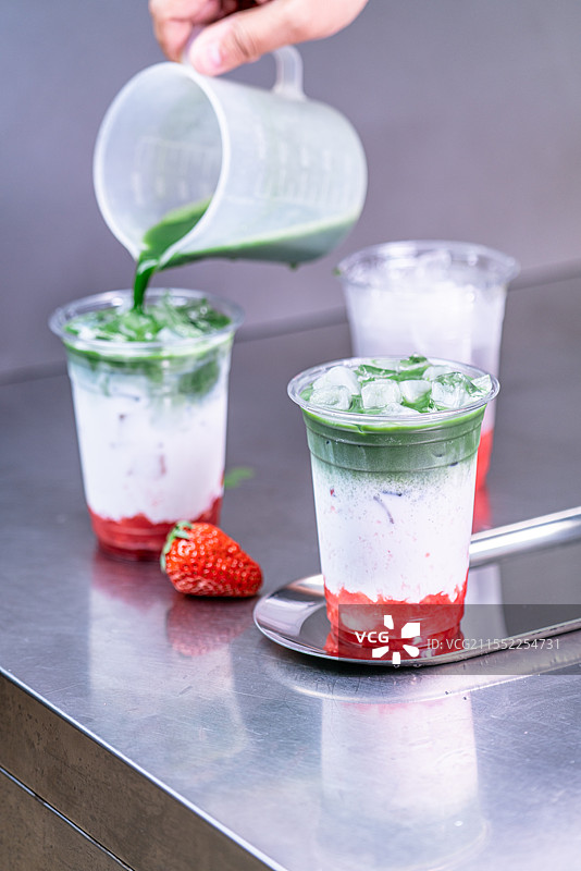 不锈钢桌子上草莓、抹茶和椰奶的饮品制作过程图片素材