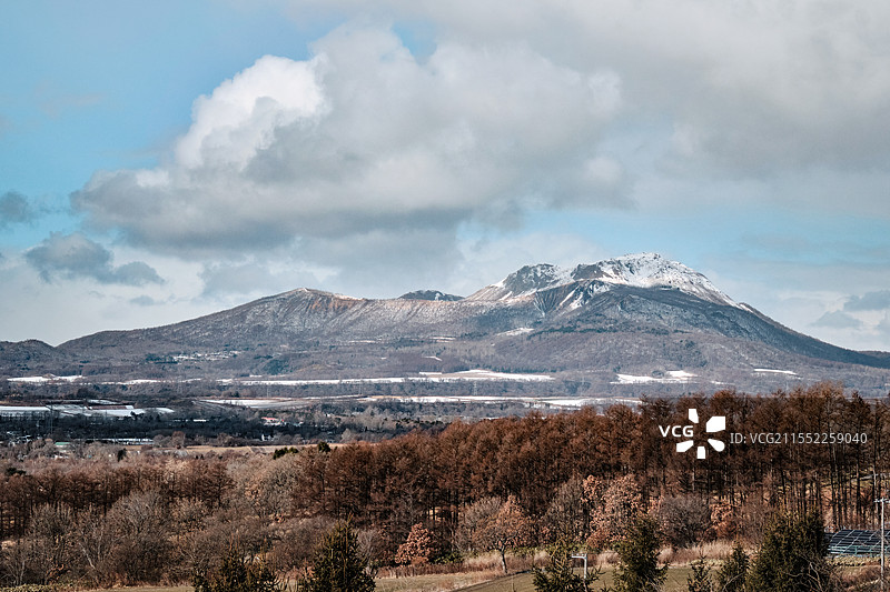 日本北海道洞爷湖町，从有珠山服务区远眺的有珠山，冬日蓝天白云下，山顶皑皑白雪图片素材
