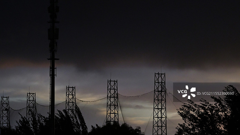 乌云压城，铁塔与树木在暮色中化为剪影。风雨欲来的时刻，世界仿佛被按下静音键，只剩寂静与深沉 。图片素材