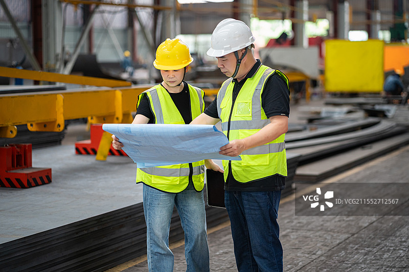 车间厂房内观看图纸沟通交流的男女工程师图片素材