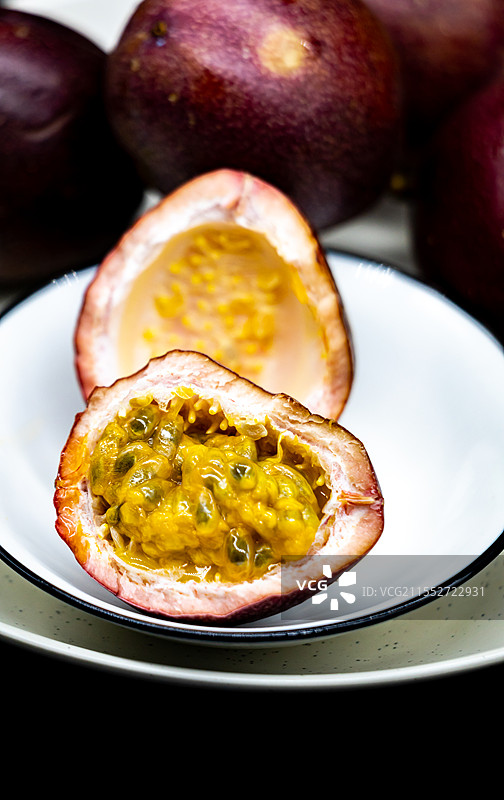 黑色背景下盘子中百香果水果的高角度视图.红色百香果与黄金百香果口味的不同之处图片素材