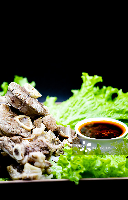 黑色背景下托盘中新疆和内蒙古草原特色美食手抓羊肉手扒肉食物蔬菜生菜特写镜头.手抓羊肉手扒肉的不同之处图片素材