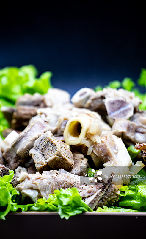 黑色背景下托盘中新疆和内蒙古草原特色美食手抓羊肉手扒肉食物蔬菜生菜特写镜头.手抓羊肉手扒肉的不同之处图片素材