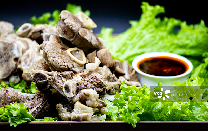 黑色背景下托盘中新疆和内蒙古草原特色美食手抓羊肉手扒肉食物蔬菜生菜特写镜头.手抓羊肉手扒肉的不同之处图片素材