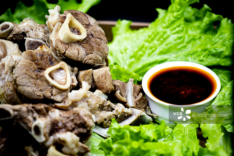 黑色背景下托盘中新疆和内蒙古草原特色美食手抓羊肉手扒肉食物蔬菜生菜特写镜头.手抓羊肉手扒肉的不同之处图片素材