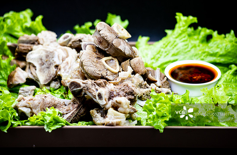 黑色背景下托盘中新疆和内蒙古草原特色美食手抓羊肉手扒肉食物蔬菜生菜特写镜头.手抓羊肉手扒肉的不同之处图片素材