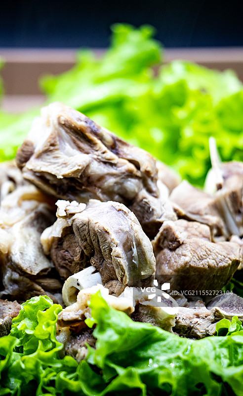黑色背景下托盘中新疆和内蒙古草原特色美食手抓羊肉手扒肉食物蔬菜生菜特写镜头.手抓羊肉手扒肉的不同之处图片素材