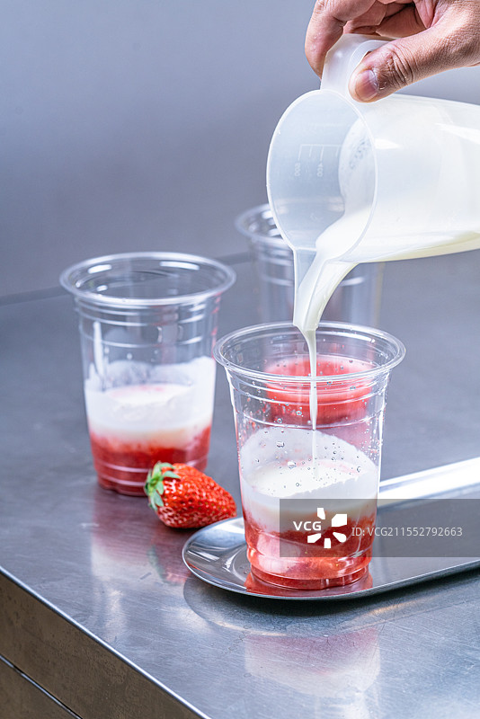 不锈钢桌子上草莓和酸奶的饮品制作过程图片素材