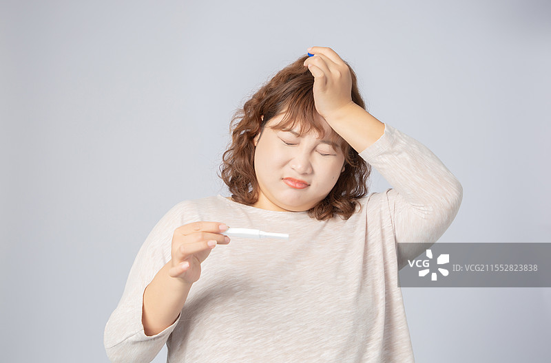 手拿验孕棒意外怀孕的亚洲肥胖女孩图片素材