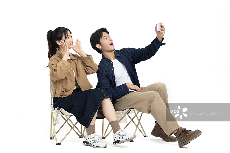 坐在一起户外折叠椅玩自拍的年轻情侣图片素材