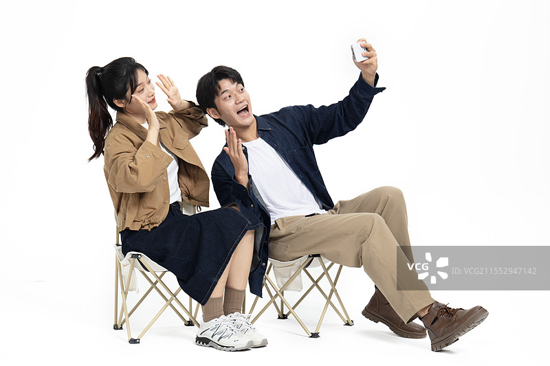 坐在一起户外折叠椅玩自拍的年轻情侣图片素材
