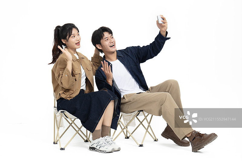 坐在一起户外折叠椅玩自拍的年轻情侣图片素材