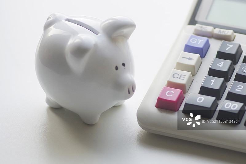 白色背景上的小猪罐和计算器的特写镜头图片素材