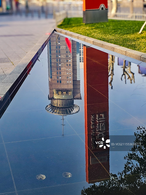 城市中一方静水，如天然镜面，映出高楼与红柱的倒影。虚实之间，是现代建筑的硬朗与水面的灵动交融。图片素材