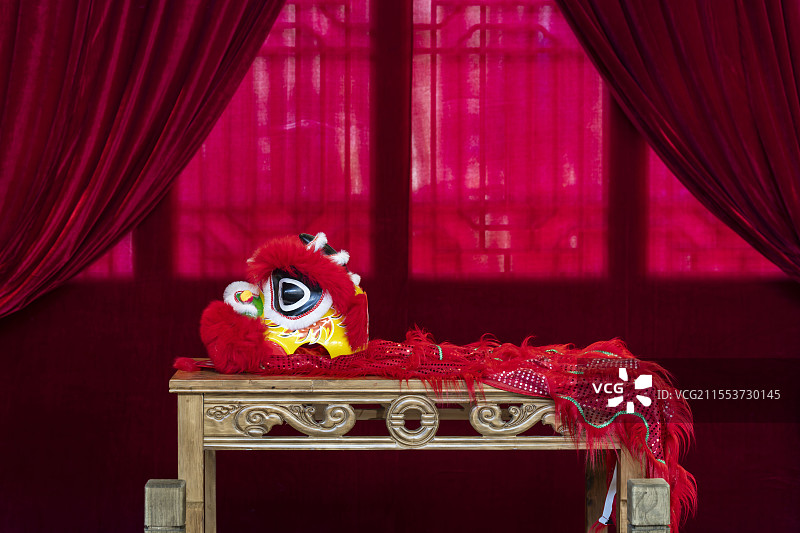 红色对称幕布前的迷你舞狮装备图片素材